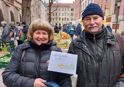 Frau und Mann Mitte 50 halten lächelnd einen Gutschein