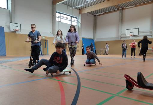 Kinder fahren auf Rollerfahrzeugen in einer Sporthalle