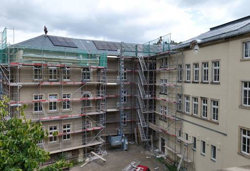 Schulgebäude mit Fassadengerüst und Solarplatten auf dem Dach
