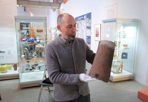 Museumsleiter Tobias Müller präsentiert einen historischen Ziegel