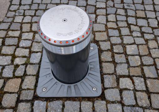 Grauer Verkehrspoller vor grauem Kopfsteinpflaster