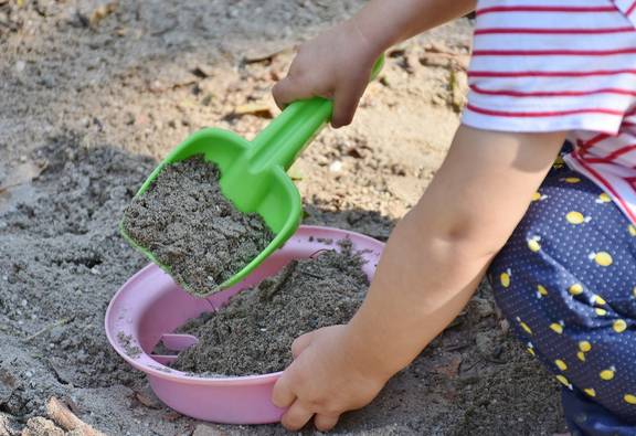 Kind spielt im Sand mit Schaufel
