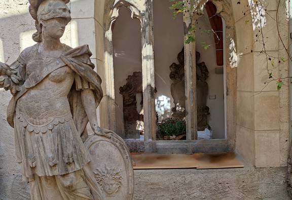 Statue neben historischem Fenster und Blattwerk